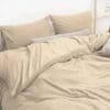 Zachte beige beddengoed set met kussens op bed.
