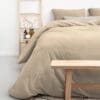 Beige dekbedovertrek op een bed met houten ladder.