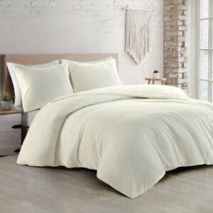 Slaapkamer met wit beddengoed en decoratieve muurhanger.